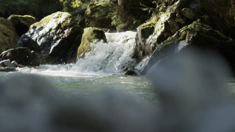 rackfocus to small waterfall at mountain stream rapids in slow motion