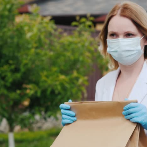 una mujer con mascarilla y guantes lleva bolsas de comida a su casa
