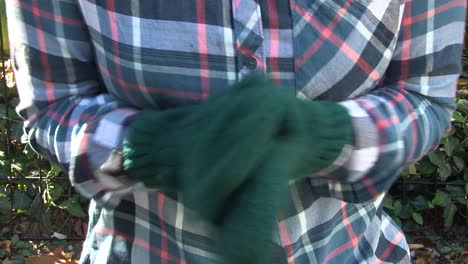 a young woman rubs her hands together in a park for warmth