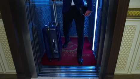 businessman in hotel. man in suit with a suitcase comes out of lift and walks along the hallway to his room. close-up.