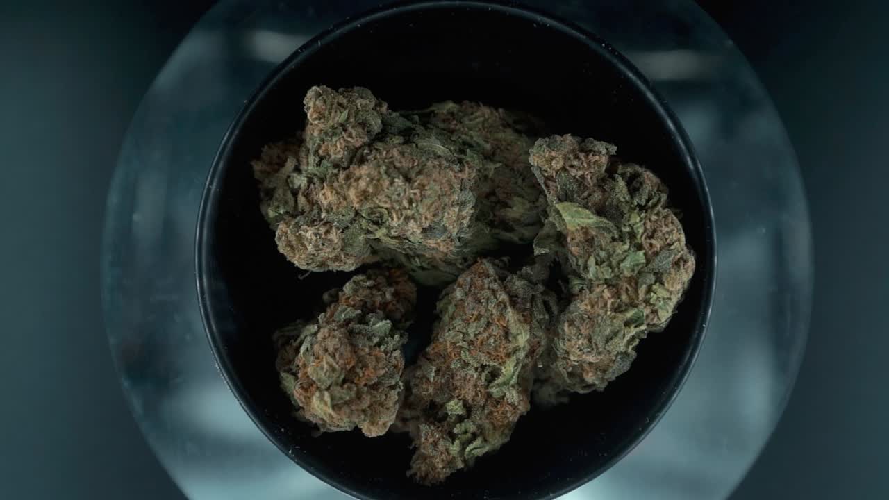 Grayish Green Dried Marijuana Buds view from above, pile of dried marijuana plants in a shiny bowl, trichomes strains, on a reflecting rotating stand, studio lights, rotating slow motion 120 fps