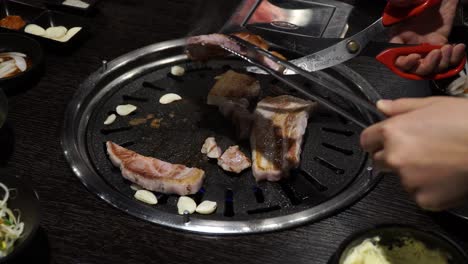 Schneiden-Von-Schweinebauch-Mit-Schere-Und-Zange-Im-Koreanischen-Grillrestaurant---Nahaufnahme