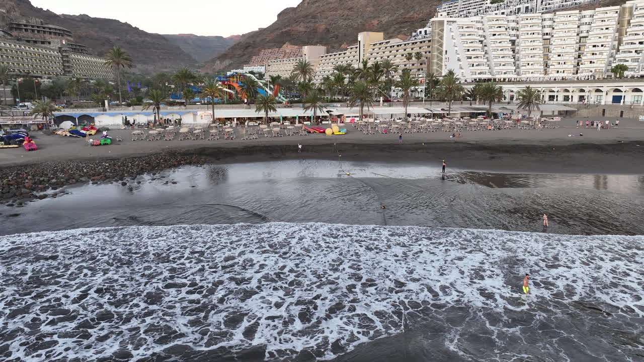 toma aerea en circulo en la orilla de la playa taurito en mogan y donde se puede ver gente bañándose