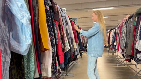a beautiful young woman is shopping in a trendy mall shopping a beautiful young woman is shopping in a trendy mall looking through hangers with different colorful clothes on hangers