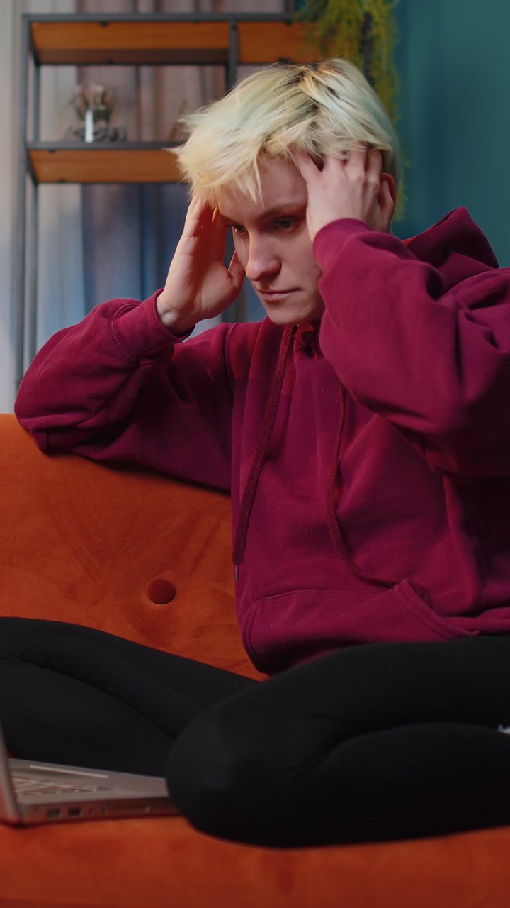 Una giovane donna stanca, freelance, usa un portatile, soffre di mal di testa, di problemi di tensione e di stress da emicrania.