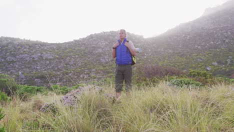 hombre excursionista senior con mochila de pie en el campo de hierba en las montañas. trekking