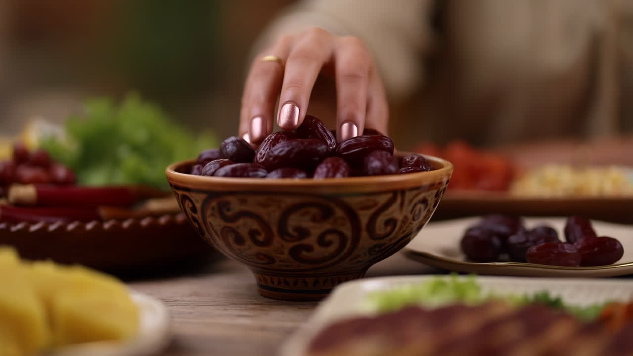 A hand picking dates from a bowl on a table