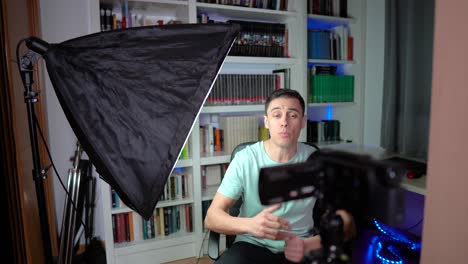 man recording video in a home studio setup with a camera and softbox