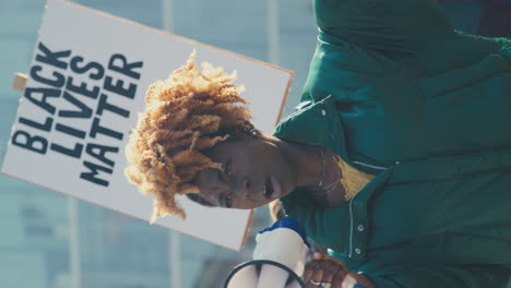 vertical video of protestors with placards and megaphone on black lives matter demonstration march