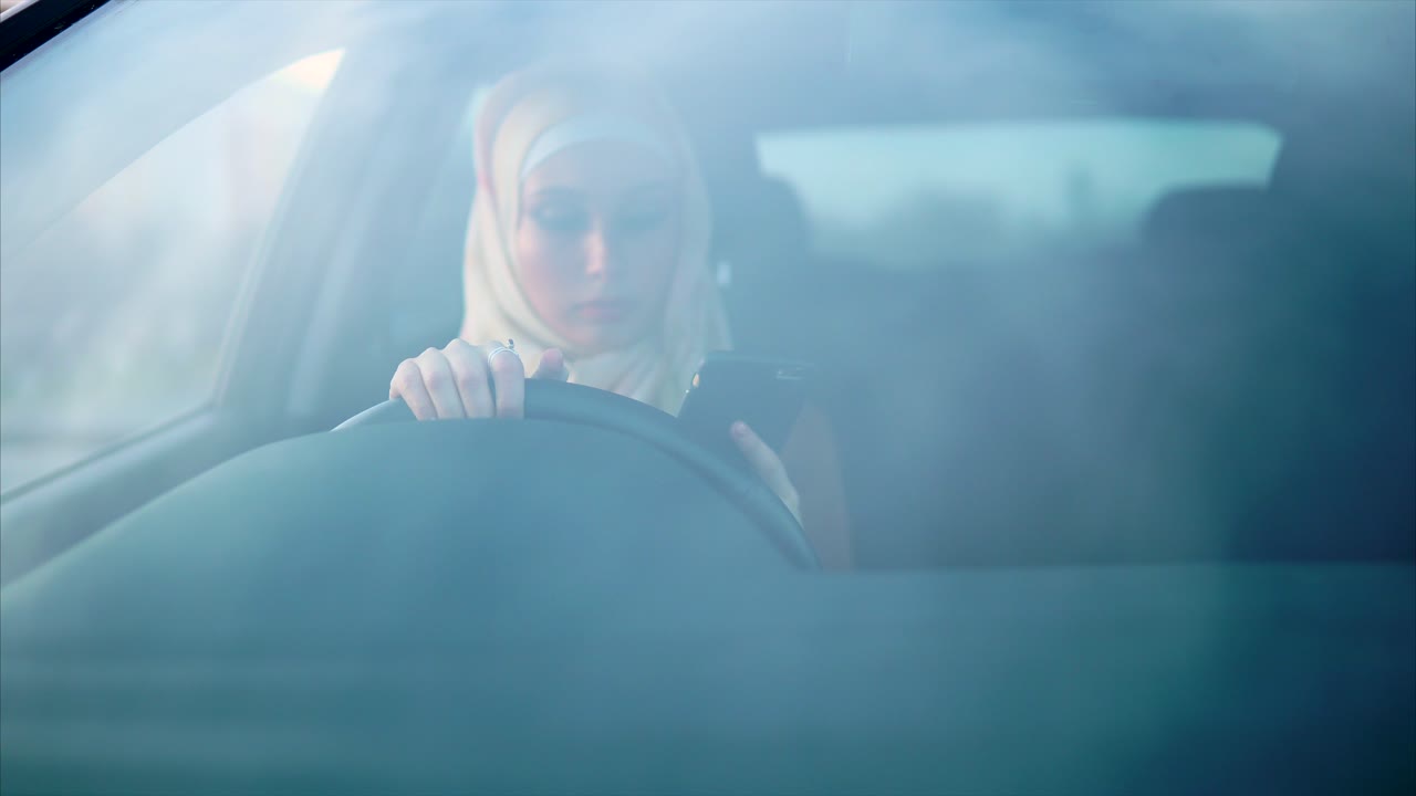 Donna alla guida di un'auto e che usa il cellulare