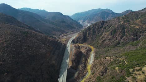 Aerial-view-of-highway-passing-through-beautiful-valley-near-river-on-high-mountains-of-Albania