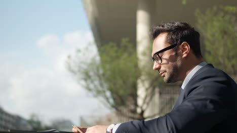 Businessman-working-with-documents,-reviewing-and-highlighting-notes-during-lunch-break-outdoors-in-a-park---profile-view