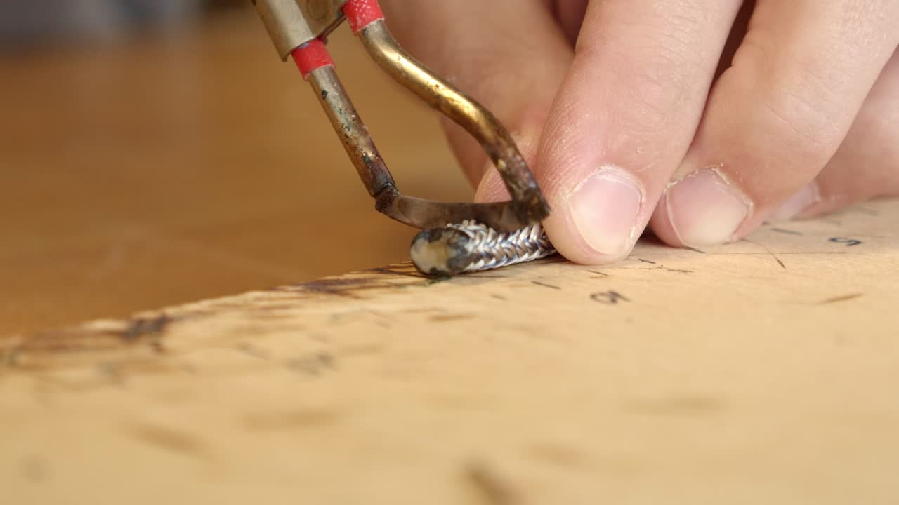 artesano que usa una herramienta de calor especial para cortar el lado de la pulsera, vista de cerca