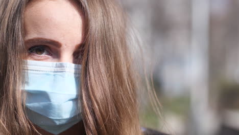 cerrar el retrato de una mujer joven con mascarilla caminando y mirando a la cámara