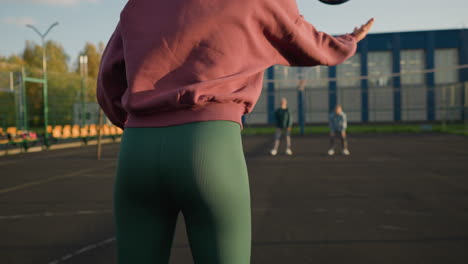 close-up of woman in green leggings bouncing volleyball, with blurred people and building in background, showcasing athleticism and outdoor activity in dynamic sports environment