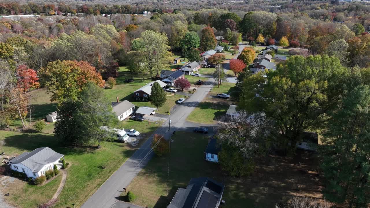Sorvolo aereo di un pittoresco quartiere periferico con alberi colorati in autunno. Splendida giornata di sole in una zona residenziale degli Stati Uniti. Campo largo. Alberi forestali e paesaggi suggestivi di giorno
