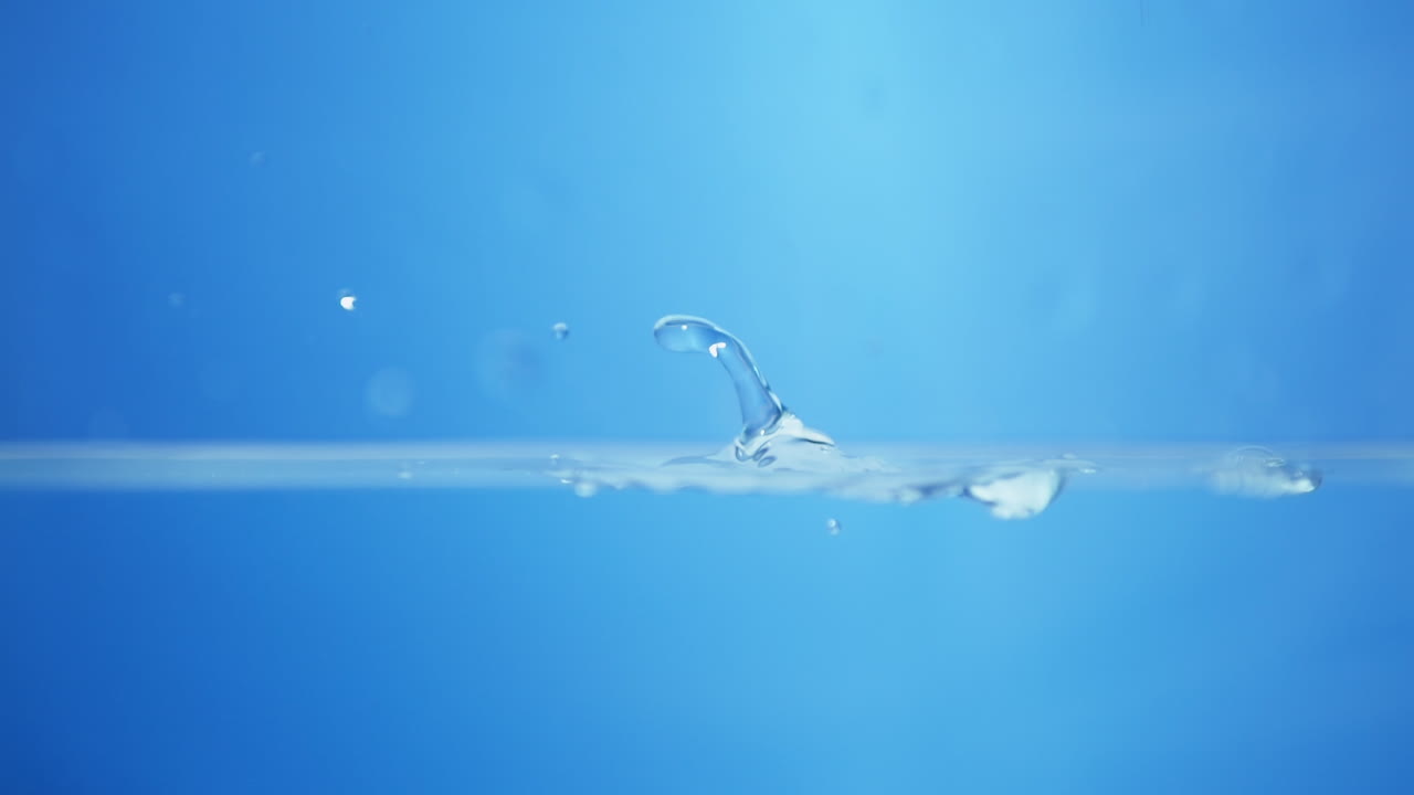 파란색 배경에 물로 가득 찬 용기에 작은 물방울과 파동을 일으키는 물 어리