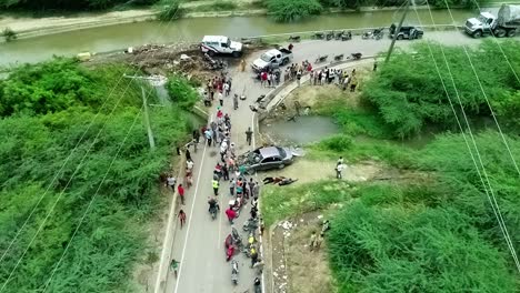 aerial view overlooking a crowd and a rescue team aiding injured people, due to a car accident, in africa - static, drone shot