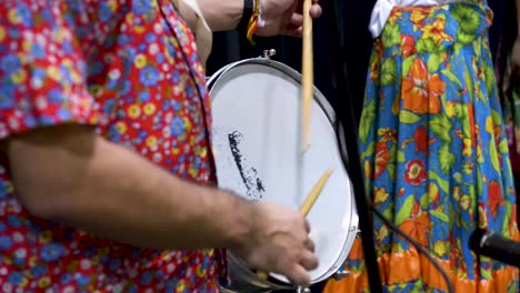 músico tocando tambor mientras la mujer baila en segundo plano.