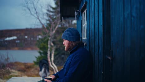 hiker drinking coffee outside a cabin in åfjord, norway - medium shot
