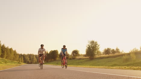 entrenamiento duro. triatleta dos ciclistas entrenando en bicicleta de carretera. dos ciclistas montados en bicicleta de ruta en el parque de la ciudad y preparándose para el triatlón. atleta fit entrenamiento intensivo dos hombres y mujeres en bicicleta antes de la competencia de triatlón