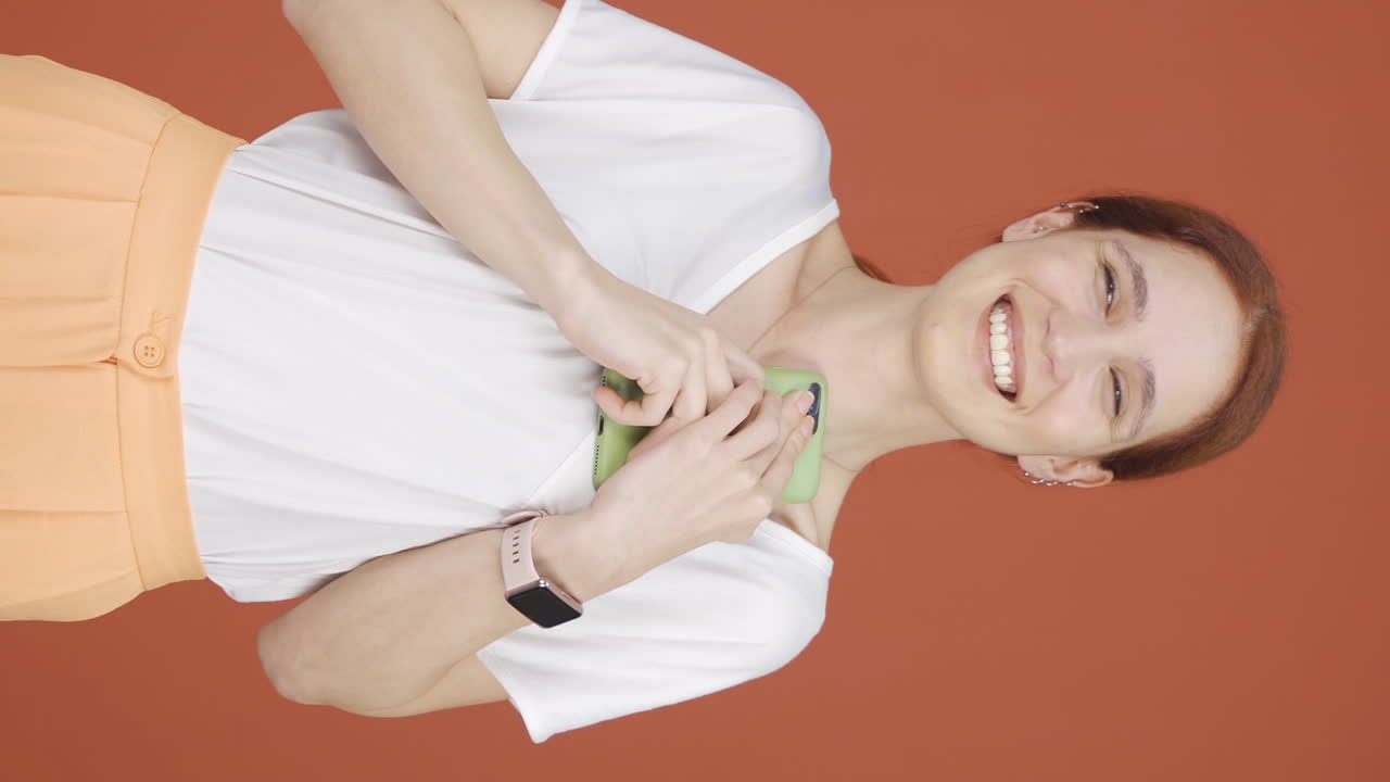 vídeo vertical de la mujer que felizmente pone el teléfono a su corazón.