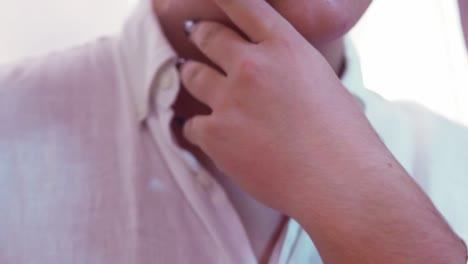 close shot of a men lgtb with a white shirt and black nails touching his neck