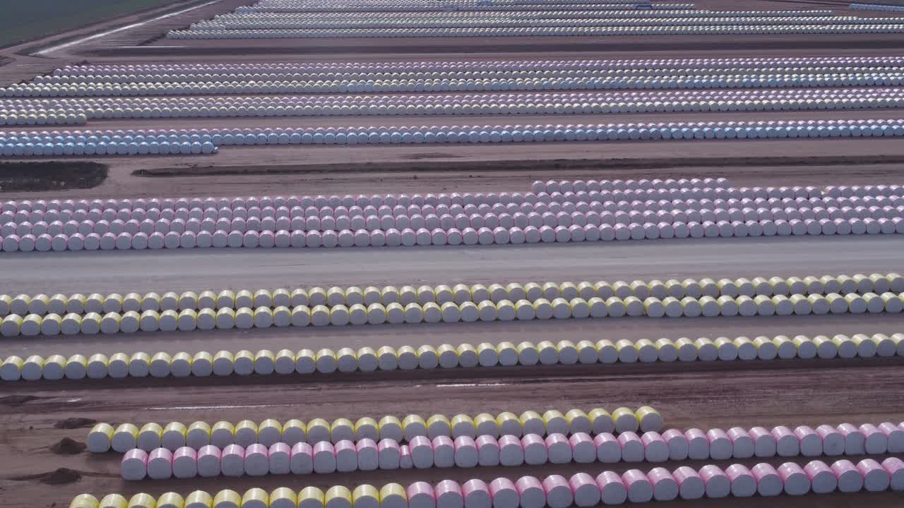 clip ascendente aéreo de filas de módulos redondos de algodón almacenados en un patio de ginebra