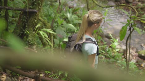 mujer rubia con mochila caminando a través de la selva tropical en costa rica