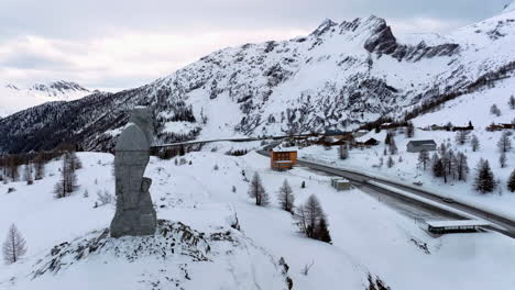 eagle sculpture of stone overlooking the simplon pass to the pass hospice with in the background the high swiss alps covered by snow