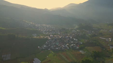 Countryside-town-surrounded-with-agriculture-fields-in-mountain-landscape,-aerial-view