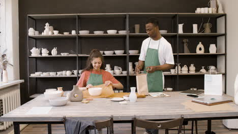 young man and woman packaging handicraft ceramics in the pottery shop