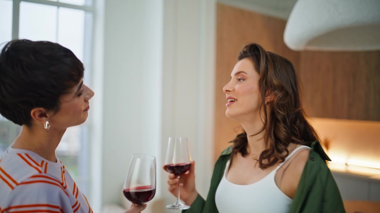 Happy two women dancing home holding wine glass closeup. Smiling couple girls