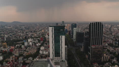 Aerial-drone-view-of-tall-modern-office-buildings-along-wide-boulevard.-Camera-view-trucking-to-right.-Dramatic-cloudy-sky-before-heavy-rain-or-storm.-Mexico-city,-Mexico.