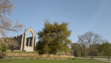 toma de establecimiento que revela las ruinas de la abadía de bolton en una hermosa y soleada mañana de verano en yorkshire, inglaterra, con un pájaro solitario volando a través del marco.