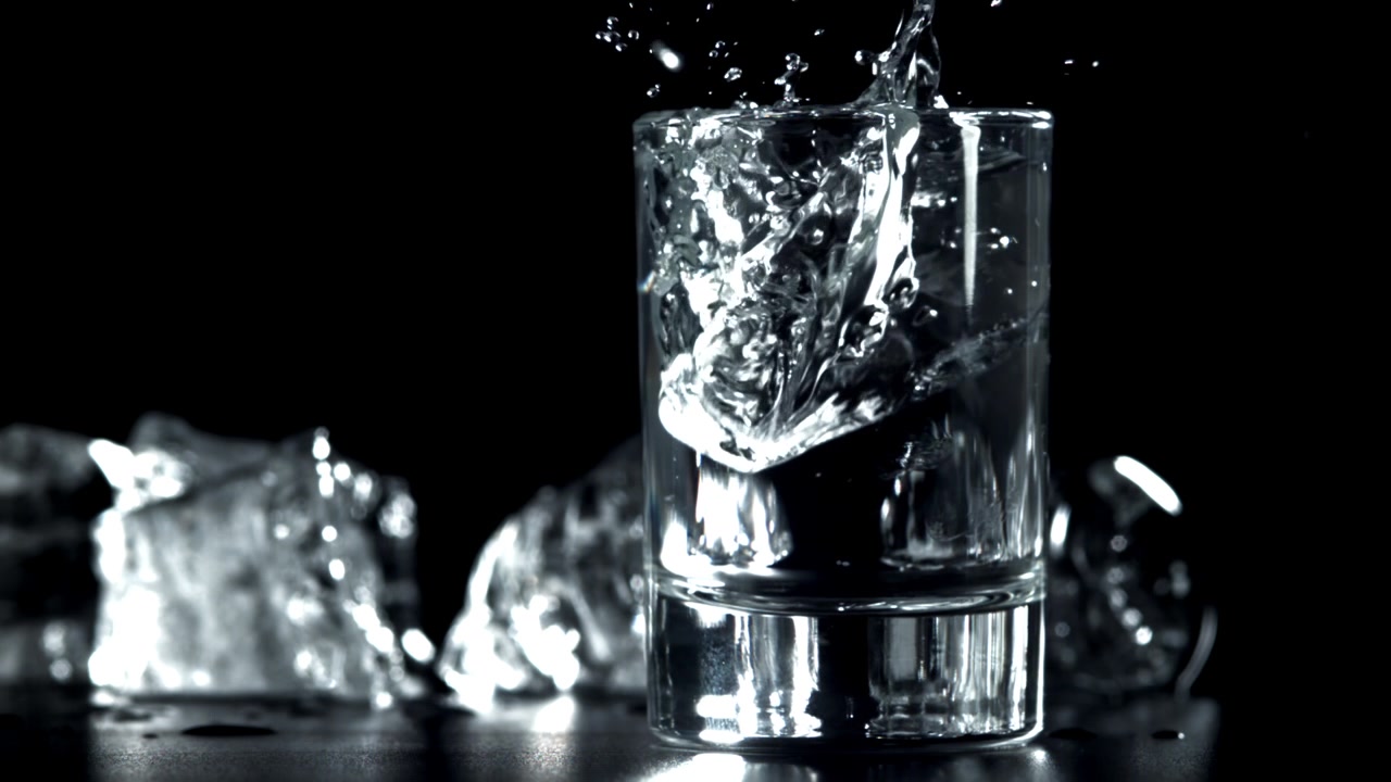 Isterninger falder ned i et glas klart vand med plask
