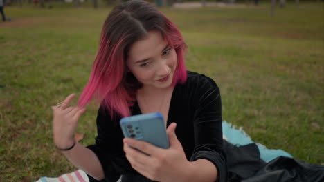 una mujer joven tomando una selfie en un parque.