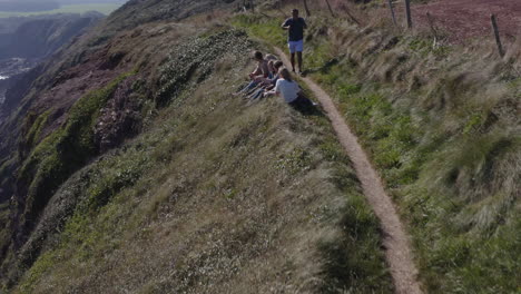 drone shot of group of friends hiking along cliffs on coastal path