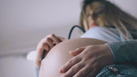 mujer embarazada pone un estetoscopio en el estómago escuchando al bebé