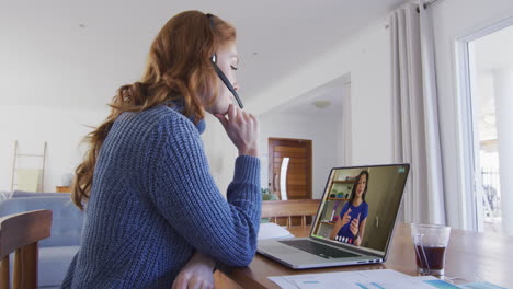 mujer caucásica con auriculares de teléfono haciendo una videollamada con una colega en una computadora portátil en casa