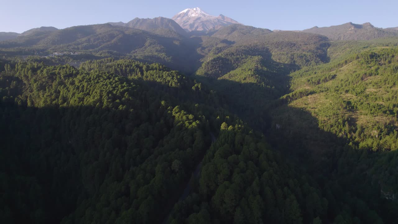 video de un avión no tripulado de una carretera a través del bosque en las colinas cerca del volcán pico de orizaba, con el volcán en el fondo