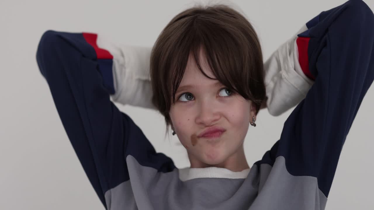 Young boy with chocolate on his face smiling with hands behind head