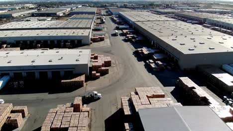 aerial view of a large distribution warehouse complex with stacked shipping containers and trucks in the yard, showcasing efficient logistics operations