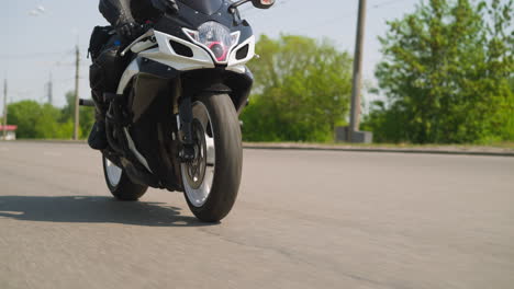adventurer drives motorcycle along empty road on sunny day