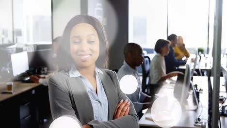 smiling businesswoman in office with colleagues working at computers in background