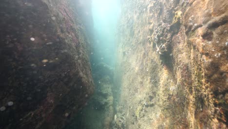 rayos de sol brillando a través de un pequeño camino en la cueva de roca submarina.