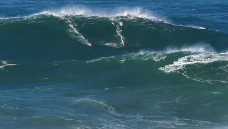 slow motion of a big wave surfers sharing a monster wave in nazaré, portugal but things go wrong