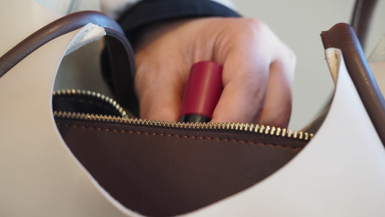 Woman putting lipstick into a bag