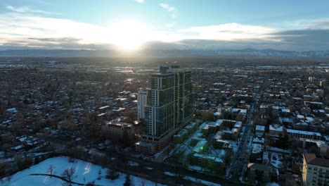 drone circling around country club towers cherry creek and slowly revealing city view of denver during sunset and mountain view at the backdrop, colorado