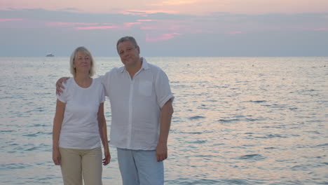 senior couple by sea looking to the camera